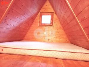 a bed in a wooden room with a small window at Vikendica Lovinovic Vlasic in Šišava