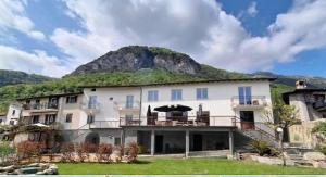 a large white building with a mountain in the background at Alpina Sanico in Toscolano Maderno