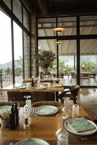 a restaurant with wooden tables and chairs and windows at Abeille Rooms in Himare