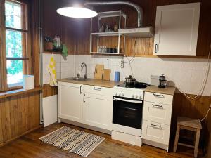 a kitchen with white cabinets and a stove at Ūbelītes in Pērkone