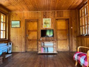 a living room with a tv and wooden walls at Ūbelītes in Pērkone