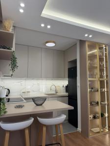 a kitchen with white cabinets and a counter with stools at Apartman Daniela Lake View in Donje Mladice