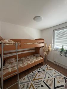 a bedroom with two bunk beds and a geometric rug at Apartman Daniela Lake View in Donje Mladice