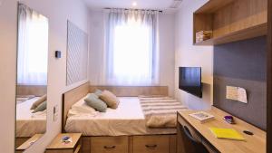 a bedroom with a bed with a desk and a window at StepHouse Pamplona in Pamplona