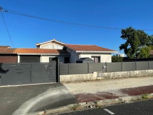 a fence in front of a house with a garage at Maison de vacances à Bordeaux in Le Haillan