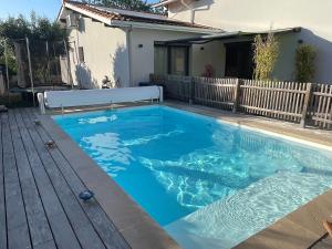 a swimming pool in a backyard with a wooden deck at Maison de vacances à Bordeaux in Le Haillan