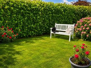 a white bench sitting in a yard with flowers at Zwischen Schlei & Ostsee in Kappeln