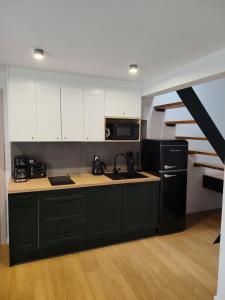 a kitchen with white cabinets and a black refrigerator at Domki u Ewy in Spychowo