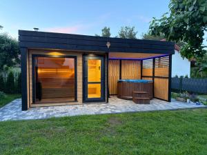 a black tiny house with a tub in a yard at Domki u Ewy in Spychowo