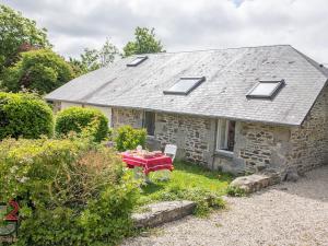 a small stone house with a red table in the yard at B&B Clerval - Maison d'hôtes et Gîtes in Dragey