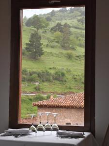 una mesa con una ventana con copas de vino. en Posada Real La Almazuela, en Montenegro de Cameros