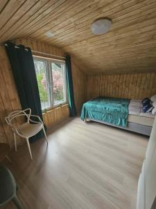 a bedroom with a bed and a chair in a room at Sosnowa Ostoja Jurata in Jurata
