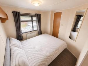 a small bedroom with a bed and a window at The Hemsbee Static caravan 117 Sandsgate Hemsby in Hemsby