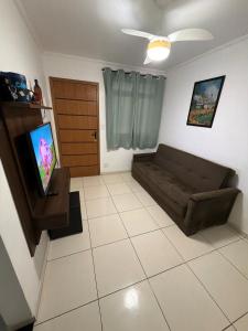 a living room with a couch and a tv at Lindo Apartamento na Guilhermina PG in Praia Grande