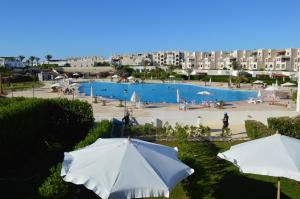 two white umbrellas in front of a swimming pool at Pool View Chalet in El Alamein