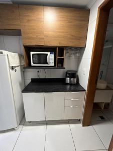 a small kitchen with a microwave on a counter at Lindo Apartamento na Guilhermina PG in Praia Grande