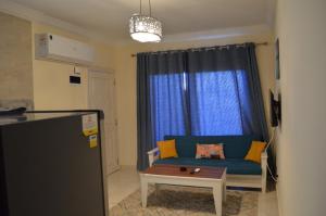a living room with a blue couch and a table at Pool View Chalet in El Alamein