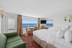 a hotel room with a bed and a couch and a table at The Corsair & Cross Rip Oceanfront in Dennis Port +127 photos