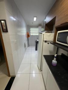 a small kitchen with a refrigerator and white tiles at Lindo Apartamento na Guilhermina PG in Praia Grande +13 photos