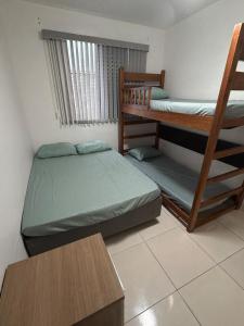 a bedroom with two bunk beds and a window at Lindo Apartamento na Guilhermina PG in Praia Grande