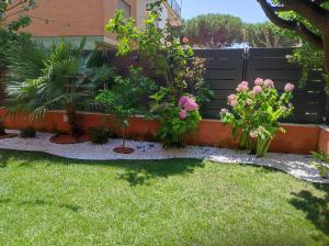 a garden with flowers and plants in front of a fence at Eden Bay Vacation Home in Ladispoli