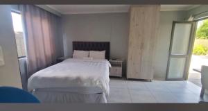 a bedroom with a white bed and a window at Rundu Rainbow Guesthouse in Rundu