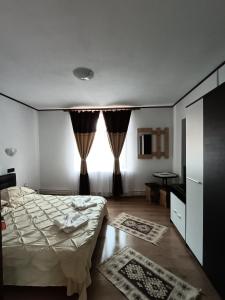 a bedroom with a bed and a window with curtains at Pensiunea Narcisa cu Ciubar in Mălăeşti +24 photos