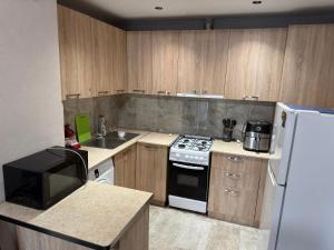 a kitchen with wooden cabinets and a white refrigerator at Didveli Mountain Apartment in Bakuriani