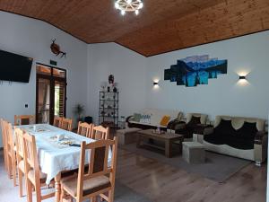 a dining room with a table and chairs and a couch at Pensiunea Narcisa cu Ciubar in Mălăeşti