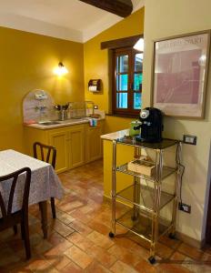 a kitchen with yellow walls and a table with a microwave at Le Case Gialle Resort in Gualdo Cattaneo