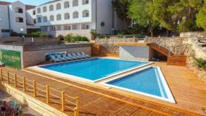 a swimming pool on a wooden deck next to a building at MOBILE HOME Nikol in Pirovac