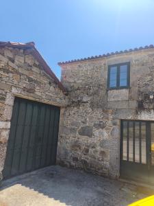 a stone building with a garage with a green garage door at Casa Pancha in Cerdeda
