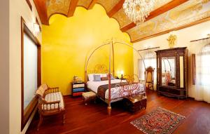 a bedroom with a bed and a yellow wall at Ginger House Museum Hotel in Cochin
