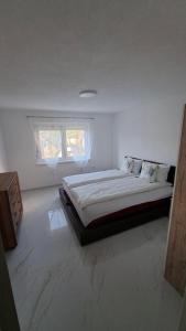 a bedroom with a large bed in a white room at Apartman Ishar in Bihać