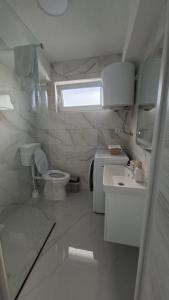 a white bathroom with a toilet and a sink at Apartman Ishar in Bihać