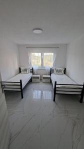 a white room with two beds and a window at Apartman Ishar in Bihać