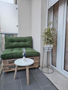 a green couch sitting on a balcony with a table at Nading flat in 'Aïn Benian