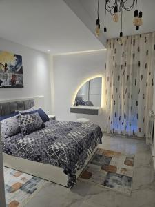 a white bedroom with a bed and a window at Nading flat in 'Aïn Benian