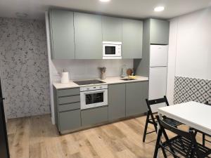 a kitchen with white cabinets and a table with chairs at VuT El Mirlo in Frías