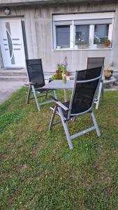 two chairs and a table in the grass at Apartman Ishar in Bihać