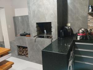 a kitchen with a fireplace with a counter top at Quarto em edícula com banheiro espaço privativo in Foz do Iguaçu