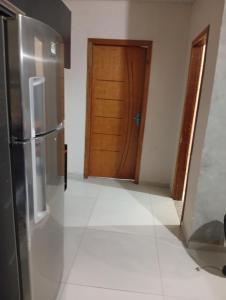 a kitchen with a refrigerator and a door at Quarto em edícula com banheiro espaço privativo in Foz do Iguaçu