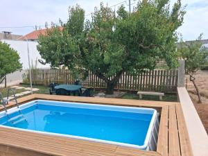a swimming pool in a backyard with a tree at Adega dos Avós - Casa completa in Alcobaça