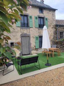 a patio with chairs and a table and an umbrella at Maison 4 à 9 personnes à la campagne in Alleuze