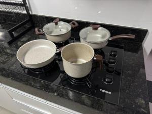 three pots and pans sitting on top of a stove at M e M executivo in Ipatinga