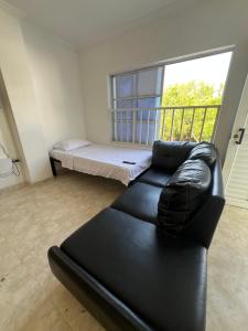 a black leather couch in a living room with a bed at Cartagena Visible Casa de Huéspedes in Cartagena de Indias +54 photos