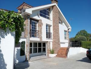 a large white house with a garage at Cumbre- chalet con piscina cubierta y vistas al mar en Sada in Sada