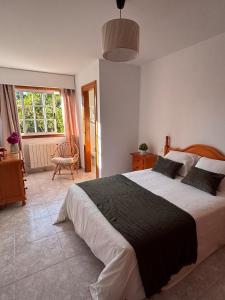 a bedroom with a large bed and a chair at Cumbre- chalet con piscina cubierta y vistas al mar en Sada in Sada
