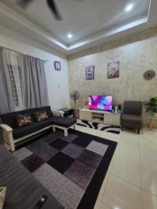 a living room with a couch and a tv at Ctr Ruby homestay in Shah Alam
