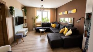 a living room with a black couch and yellow pillows at Bytča Central Apartment in Bytca